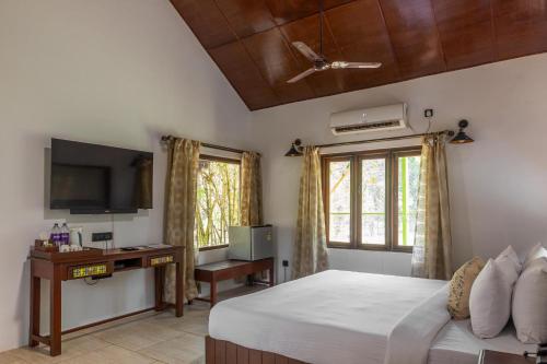a bedroom with a bed and a desk and a television at WilderNest Araanya by Vibescapes in Karjat