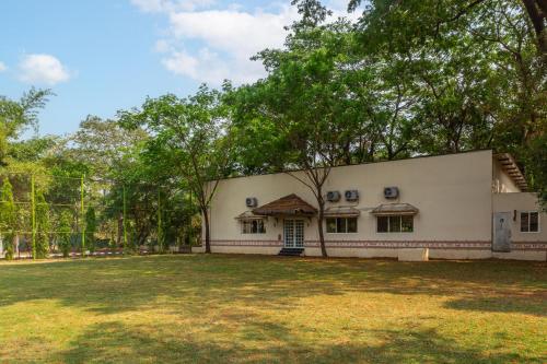 a large white building with trees in front of it at WilderNest Araanya by Vibescapes in Karjat