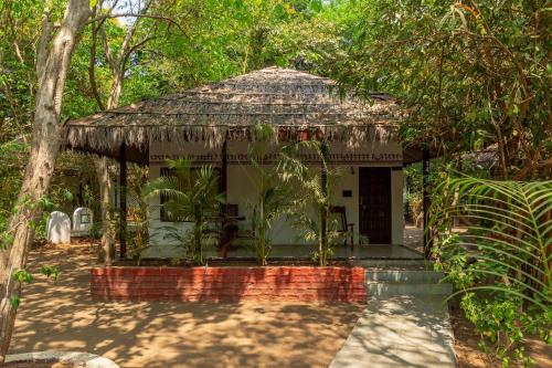 a small hut with a roof in a forest at WilderNest Araanya by Vibescapes in Karjat