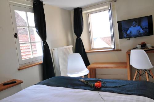 a bedroom with a bed and two windows and a television at Les Glycines Vézelay in Vézelay