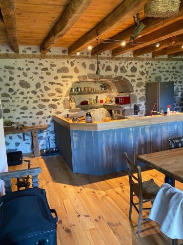 une cuisine avec un comptoir, une table et des chaises dans l'établissement La ferme du Liaumiers, à Saint-Cirgues-de-Jordanne