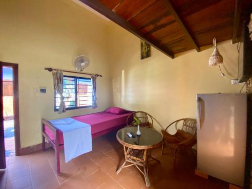 a room with a pink couch and a table and a window at Derm Svay Guesthouse - yoga & cafe in Kampot
