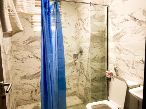 a shower with a blue shower curtain in a bathroom at City King Hotel in Kano