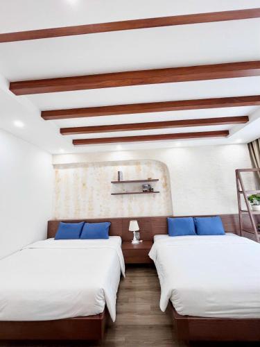 Cette chambre comprend 2 lits avec des draps blancs et des oreillers bleus. dans l'établissement Chuỗi Villa Sun Feria 4 Ngủ OCE - Bể Bơi - Gần Biển - Trung tâm Bãi Cháy, à Hạ Long