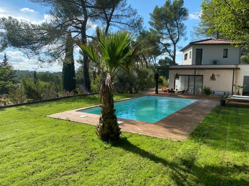 une maison avec une piscine et un palmier dans la cour dans l'établissement Le Secret des Pins, à Pernes-les-Fontaines