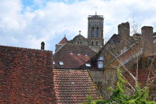 a building with a clock tower and roofs at Les Glycines Vézelay in Vézelay