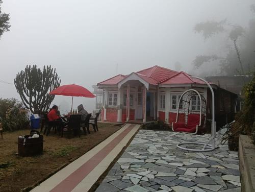 a house with people sitting at a table under an umbrella at Maliani Farms in Takdāh
