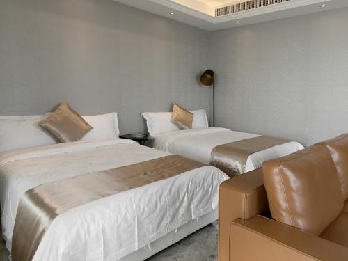 a hotel room with two beds and a couch at Pengman Beijing Road A-mall Apartment - Free Shuttle to Canton Fair in Guangzhou