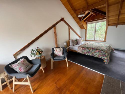 a bedroom with a bed and two chairs at Gaol House Cottages in Bicheno