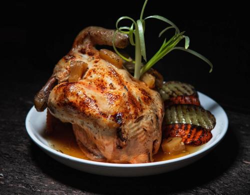 a roast chicken on a white plate with pickles at Forest Camp in Valencia