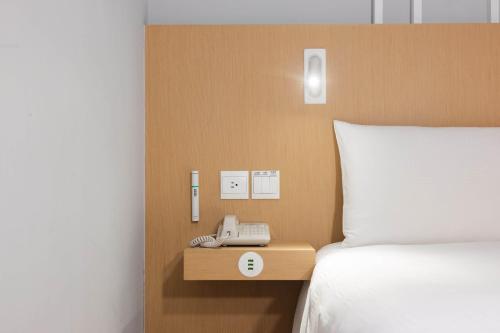 a bed with a phone on a night stand next to a bed at HOTEL PIN Jiaoxi in Jiaoxi