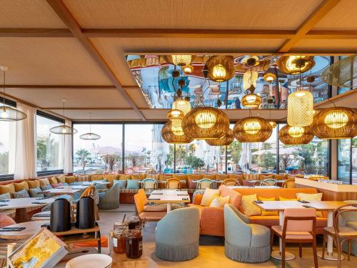 a restaurant with tables and chairs and chandeliers at Mercure Villeneuve Loubet Plage in Villeneuve-Loubet