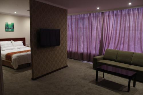 a bedroom with a bed and a couch and a tv at GreenTree Inn Nanjing Yuhuatai Scenic Spot China Gate Subway Station Express Hotel in Nanjing