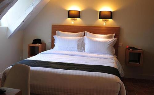 a bedroom with a large bed with two lights above it at Les Glycines Vézelay in Vézelay