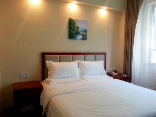 a bedroom with a bed with white sheets and a picture on the wall at GreenTree Inn Nanjing Yuhuatai Scenic Spot China Gate Subway Station Express Hotel in Nanjing