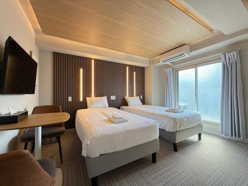 a hotel room with two beds and a table at Osaka Ebisu Hotel in Osaka