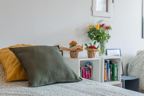 a bed with a green pillow and a book shelf with books at La Bergerie des Cimes in Lantosque