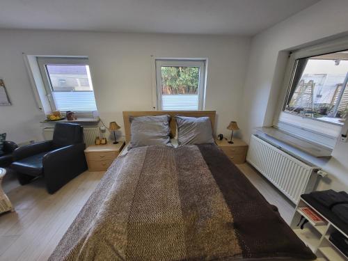 a bedroom with a large bed with a chair and windows at Eulennest Nassau in Weikersheim