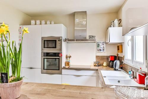 une cuisine avec des armoires blanches et des appareils en acier inoxydable dans l'établissement Les Pinsons - Jardin - Parking - Wifi, à Challans