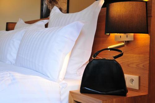 a black purse sitting on a bed with white pillows at Les Glycines Vézelay in Vézelay