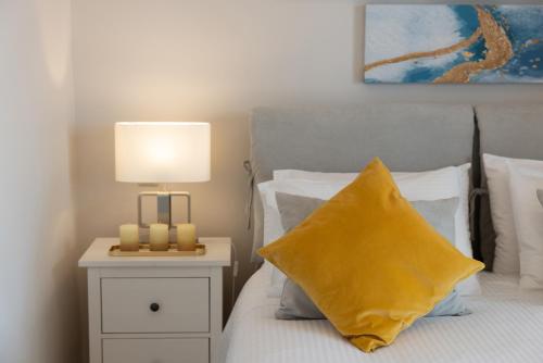 a bed with a yellow pillow and a lamp on a night stand at Unique apartment in Corfu Town