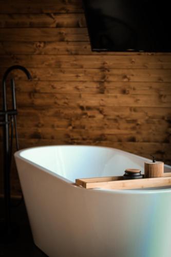 a white bath tub in a room with a wooden wall at Perryland Urban Farm in Piatra
