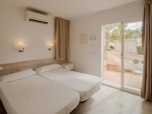 a white bedroom with a bed and a large window at Sun Club El Dorado - All Inclusive in Llucmajor