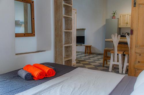 a bedroom with a bed with orange sheets and a kitchen at Maria-Anna Traditional Island House in Parikia