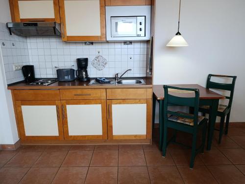 una cucina con lavandino, tavolo e forno a microonde di Haus Meeresblick WM510 a Kühlungsborn