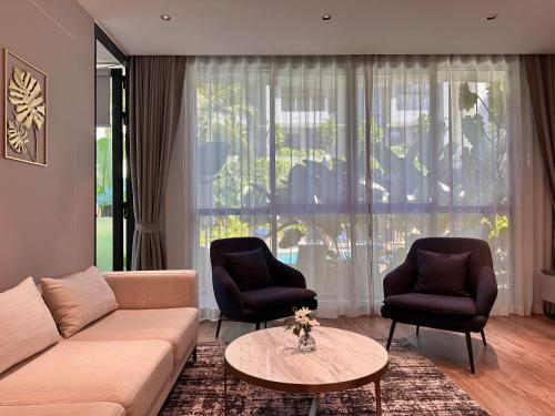 a living room with a couch and two chairs and a table at La Green Hotel and Residence in Bang Tao Beach