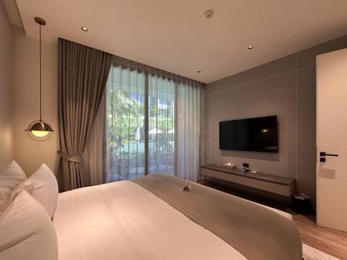 a bedroom with a large bed and a flat screen tv at La Green Hotel and Residence in Bang Tao Beach