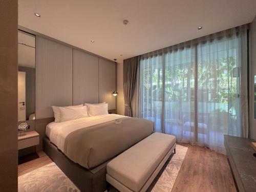 a bedroom with a large bed and a large window at La Green Hotel and Residence in Bang Tao Beach