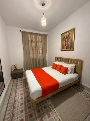 a bedroom with a bed with an orange and white blanket at Fi Makanina in Tunis