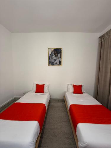 two beds in a room with red and white sheets at Fi Makanina in Tunis
