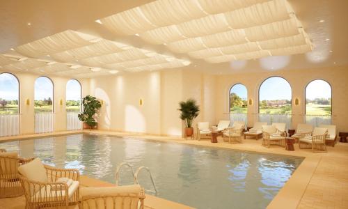 a large swimming pool with chairs and tables and windows at Hôtel Maison Chiberta I Ouverture été 2025 in Anglet