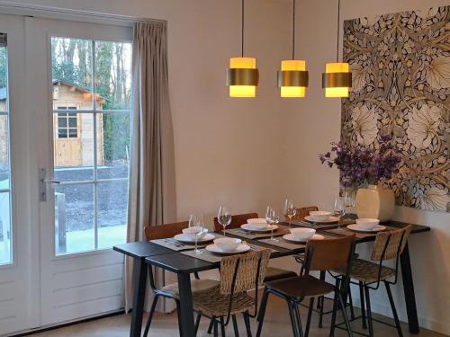 a dining room with a table and chairs and a window at Luxe wellnesshuis Drenthe met sauna, whirlpool en omheinde tuin VP048 in Hoogersmilde