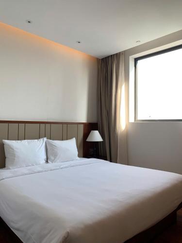 a bedroom with a large white bed with a window at Green Beach Hotel Nha Trang in Nha Trang