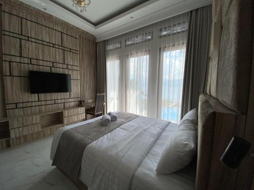 a bedroom with a large bed with a tv on the wall at Toba Retreat Mansion and Villas in Tomok