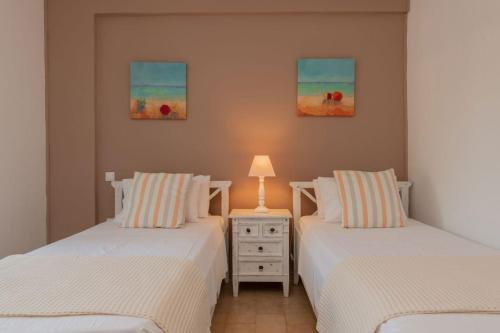 une chambre avec deux lits et une lampe sur une table de chevet dans l'établissement Villa Harmony, à Amoudi