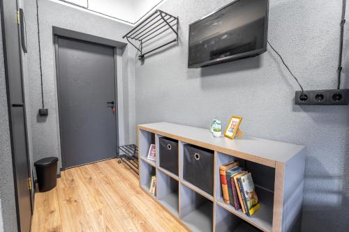 a room with a tv on a wall with a book shelf at Hotel Tērbata in Valmiera