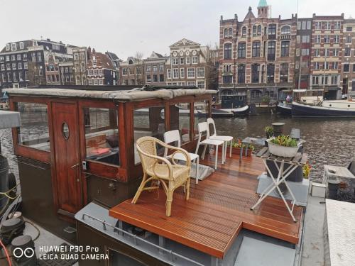 a boat with chairs and a deck on the water at Waterloo square river vieuw houseboat in Amsterdam