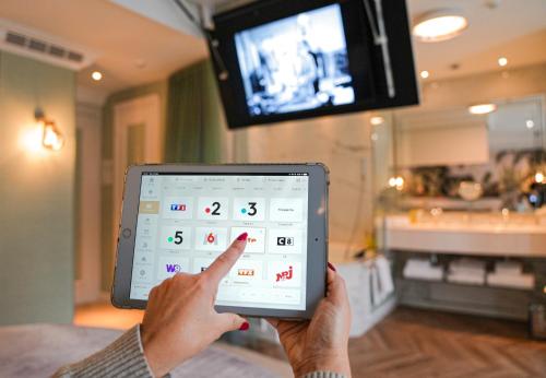 a person holding up a tablet in a room at Paris j'Adore Hotel & Spa in Paris