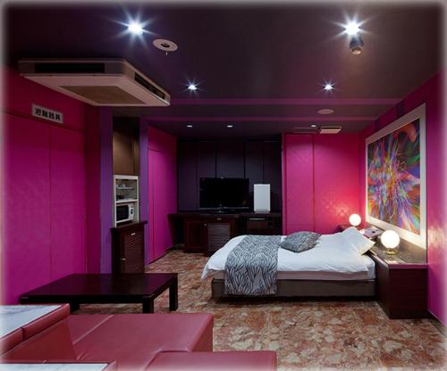 a bedroom with pink walls and a bed and a table at HOTEL TWO in ONE Hiroshima-AdultOnly in Hiroshima