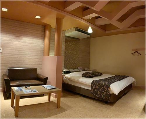 a bedroom with a bed and a chair and a table at HOTEL TWO in ONE Hiroshima-AdultOnly in Hiroshima
