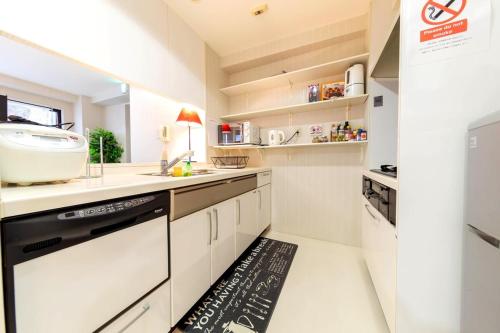 a kitchen with white cabinets and a black dishwasher at Ragsus3F ラグザス3F in Osaka