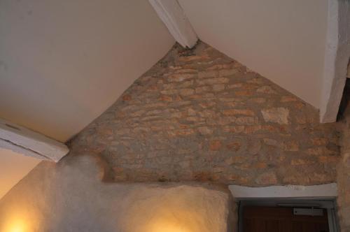 a room with a stone wall and a ceiling at Les Glycines Vézelay in Vézelay