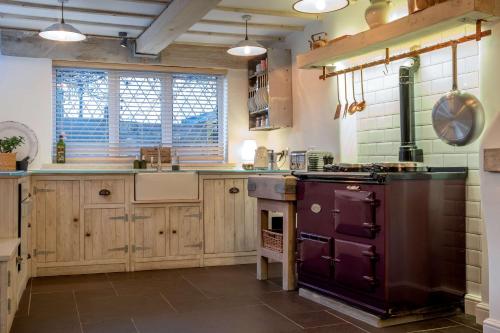 Il comprend une grande cuisine équipée d'une cuisinière violette. dans l'établissement Purple Poppy Cottage, à Burton Joyce