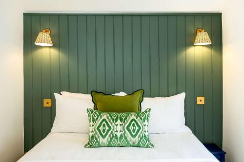 a bed with a green headboard and two lights at Purple Poppy Cottage in Burton Joyce