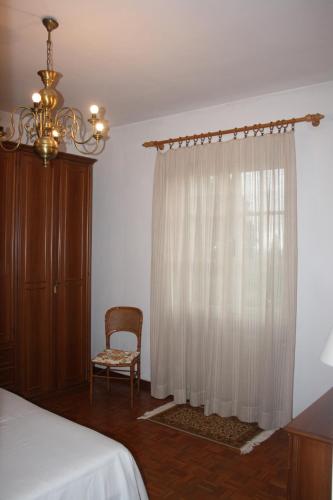 a bedroom with a bed and a chair and a window at Tenuta Poggio alla Farnia in Fauglia