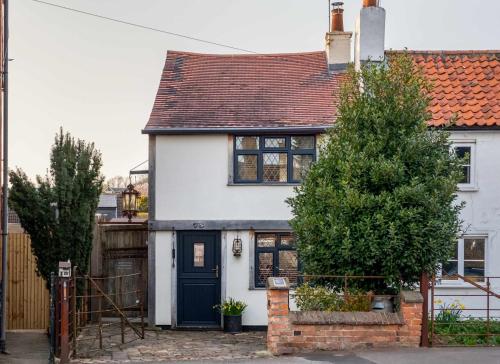 a white house with a blue door at Purple Poppy Cottage in Burton Joyce